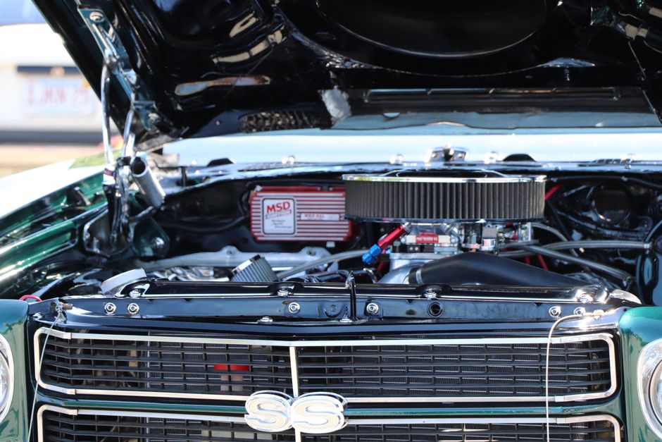 Detailed view of a classic car's engine displayed with the hood open, showcasing mechanics.